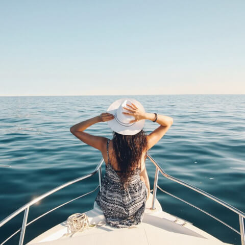 woman sitting on the bow of a boat in the middle of the ocean