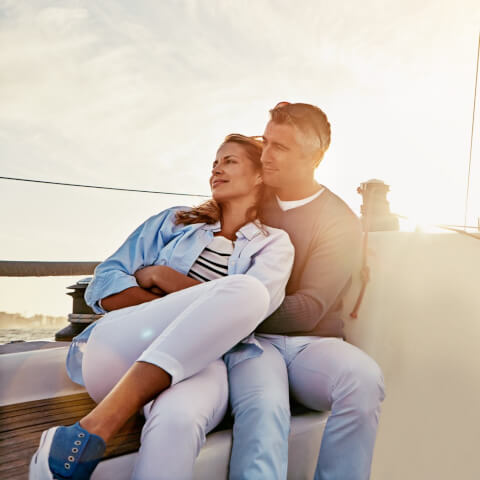a man and woman enjoying the view and embracing on a boat