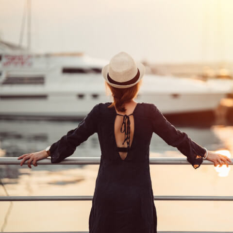 woman holding onto rails looking towards a marina