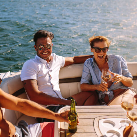 four friends having beer and wine on a boat and chatting together