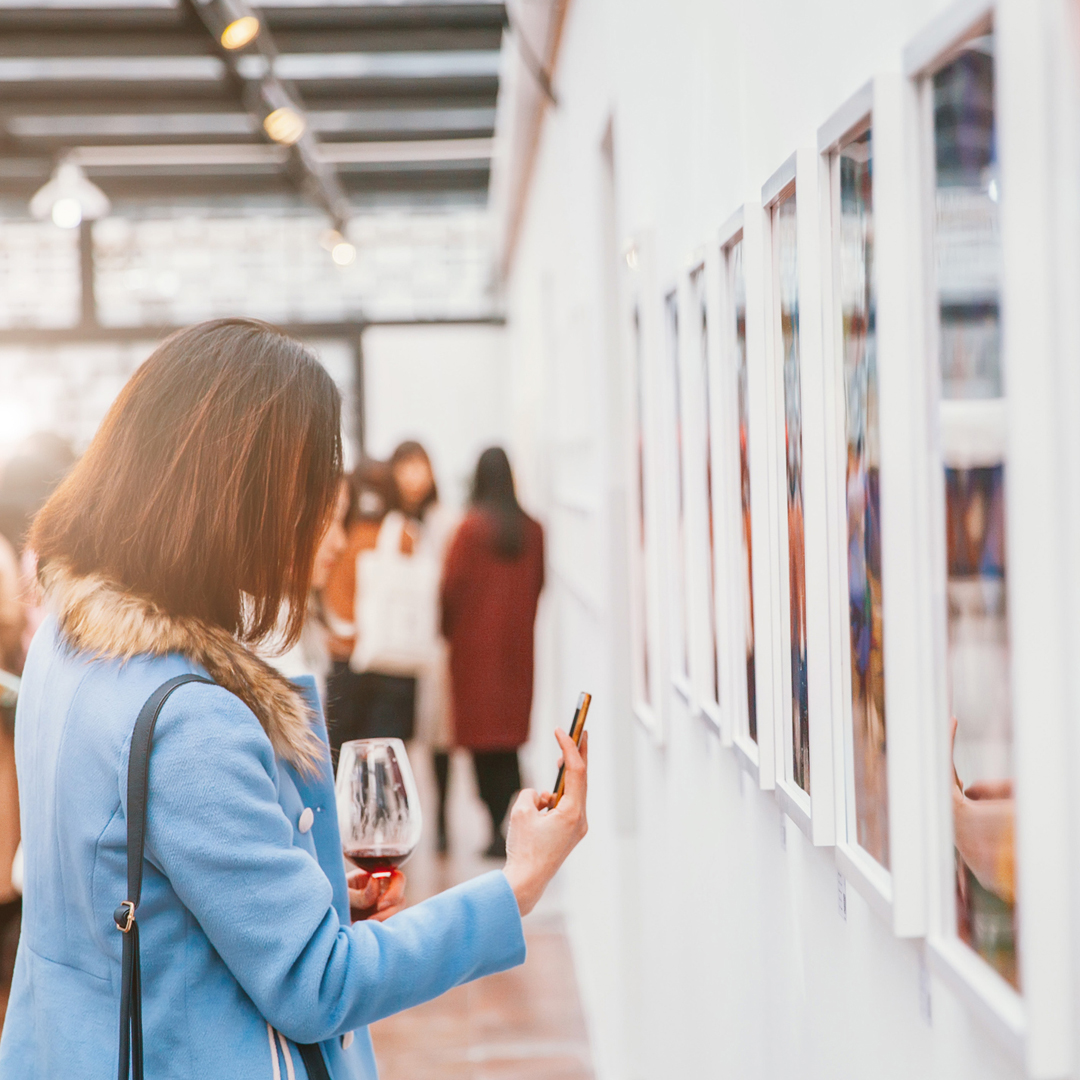 a girl in an art gallery taking a photo of a piece