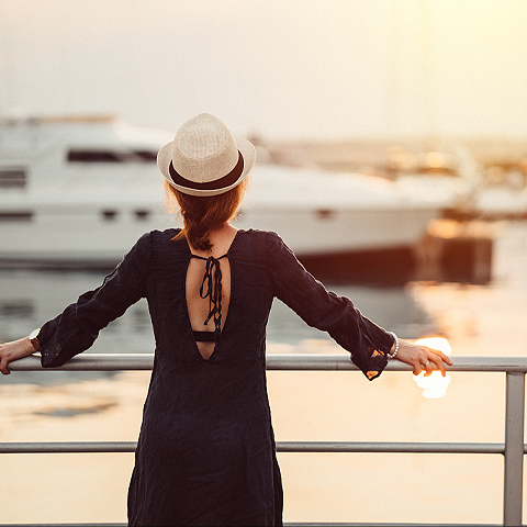 woman holding onto rails looking towards a marina