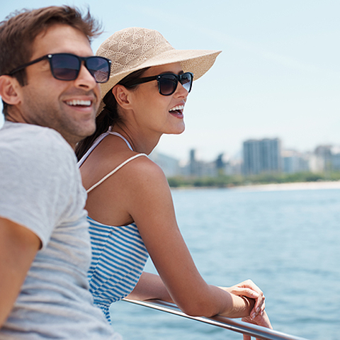 couple laughing while standing at the rails of a boat