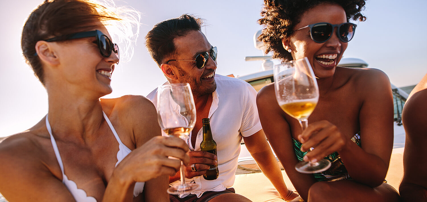 three friends laughing while drinking champagne on a boat