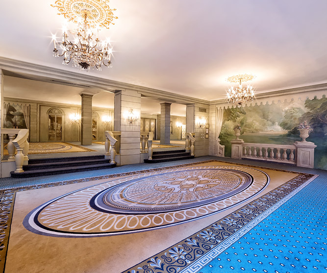 foyer with intircate carpet floors and chandeliers above