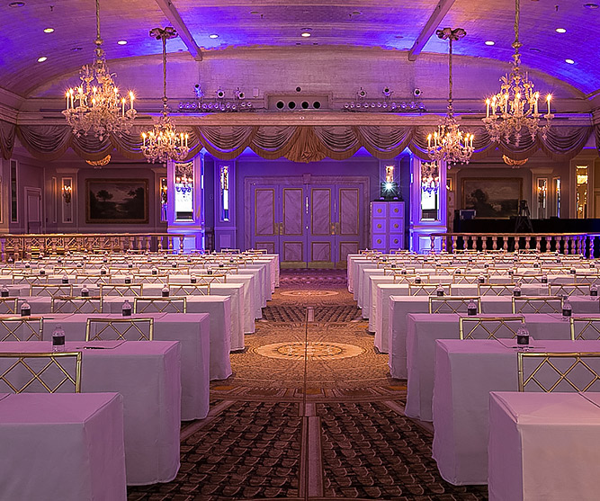 ballroom with purple lights and rows of long tables