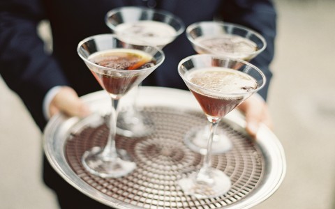 Closeup of a man holding a tray with cocktails on top