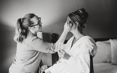 A woman getting her make up done by another woman 