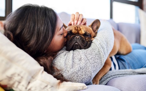 girl giving her dog a kiss on his cheek