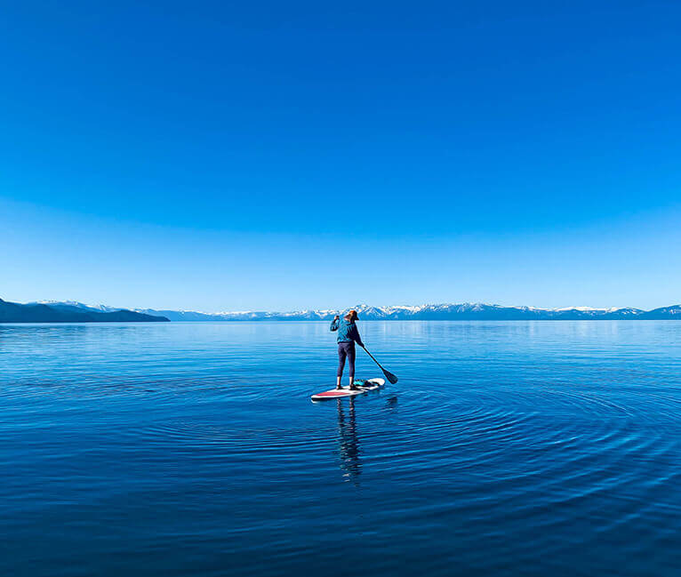 A person standing on a paddle board in the middle of a lake