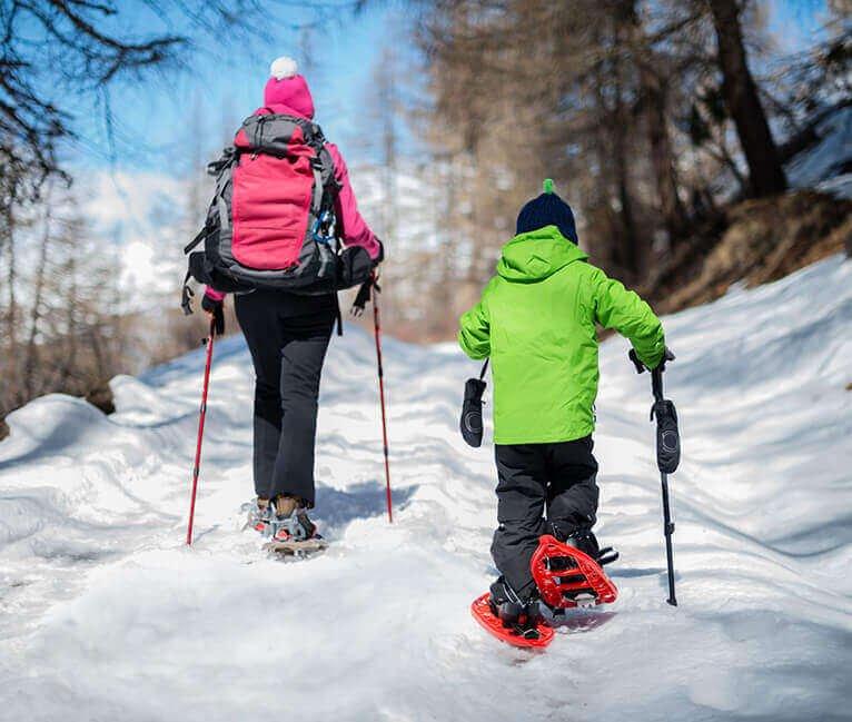 Back view of a mom and his son walking through snow