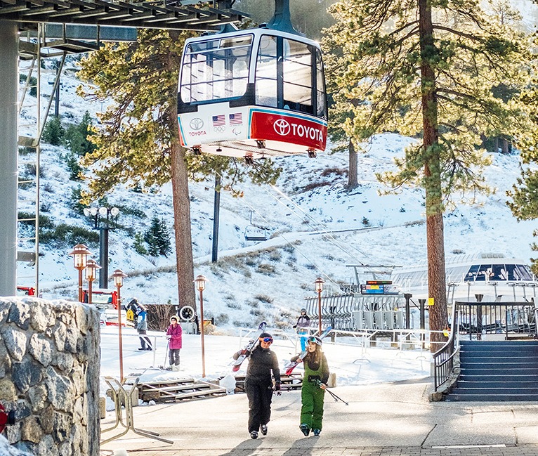 View of two woman wearing a snow suit and some ski elements walking near an aerial tramp