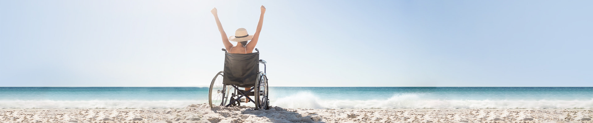 woman in a wheelchair enjoying the sea and with her hands up