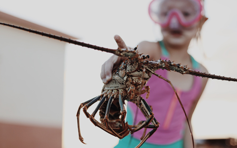 girl in goggles holding lobster