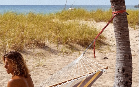 man iwith long hair in hammock at beach