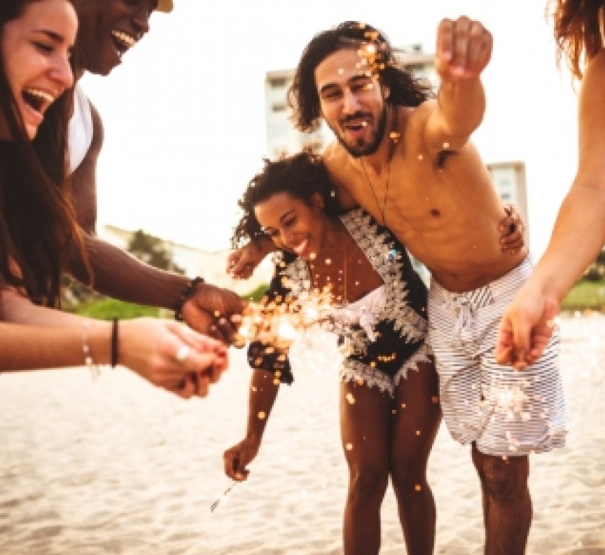 young people with sparklers on beach