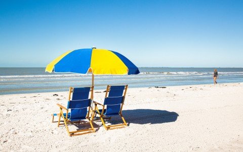 Beach chairs with umbrella in front of loungers next to the ocean  