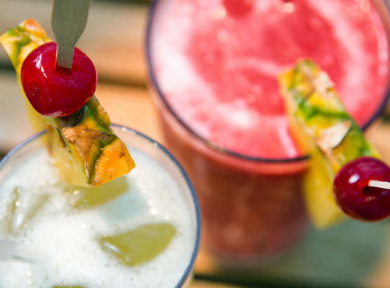Close up of smoothies with pineapple wedge on the edge 
