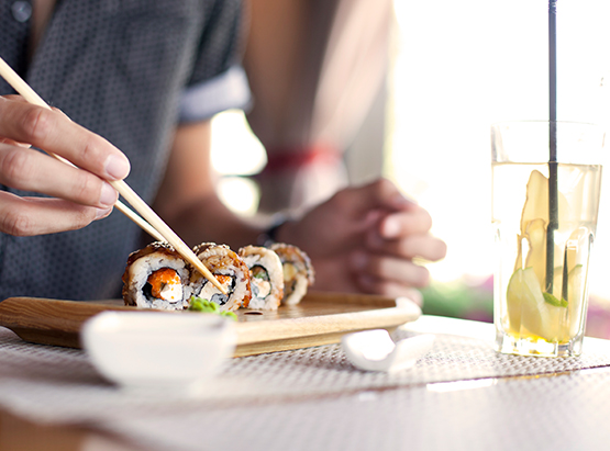 Man grabbing piece of sushi roll with chopsticks 