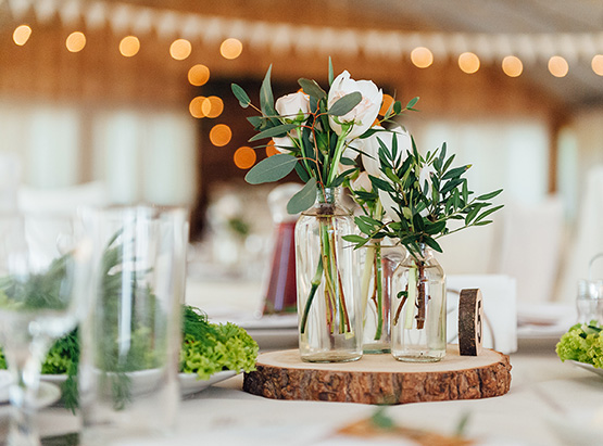 Small wooden stump on table with glass vases with white roses