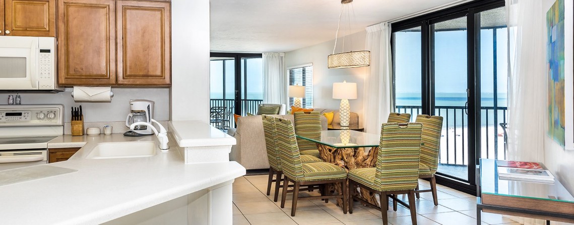 suite kitchen with bar stools, dining room table and sliding glass doors leading to the balcony