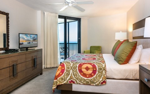 suite with king bed and sliding glass door that leads to balcony