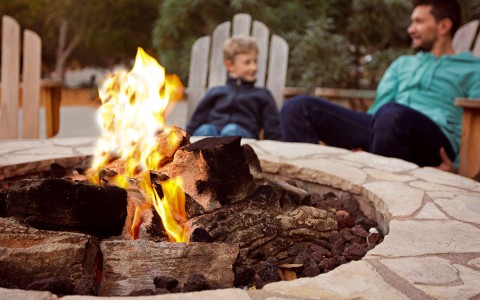kid and parent sitting around firepit