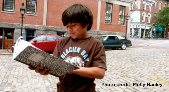 Little boy looking through his composition book outside