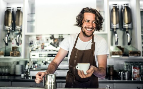barista with brown apron smiling