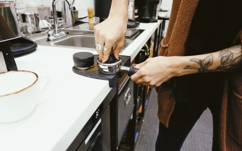 barista filling the machine with new ground coffee`