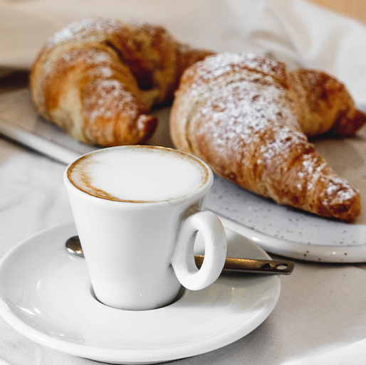 white mug with latte and two pastries in the background