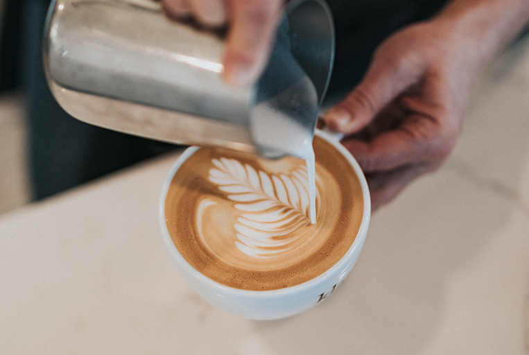 barista adding latte art into a mug