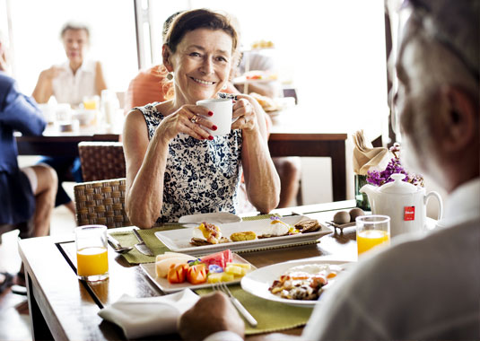 women enjoying a cup of coffee and breakfast accross companion