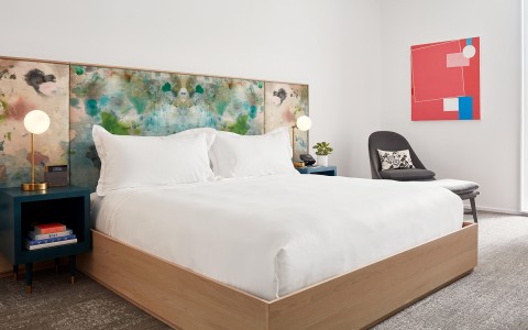 View of a large white bed and a pink painting 