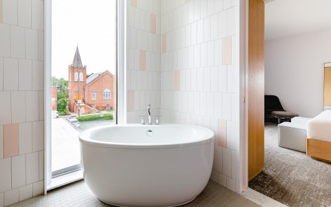 View of a bathtub next to a big window 