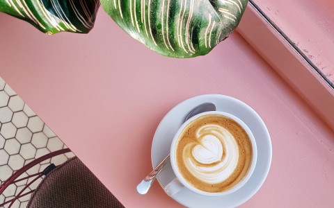 Top view of a cup of coffee on a pink surface 