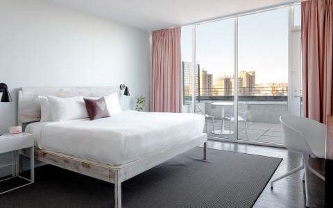 Internal view of a room with a big white bed and an excellent city view