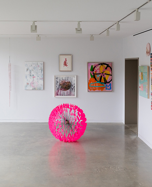paintings hanging on the wall and a pink ball sculpture in the middle