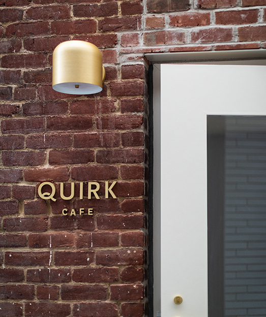 Closeup of a bricked wall with a sign that says Quirk Cafe