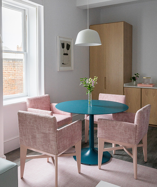 View of a dining table and some pink chairs 