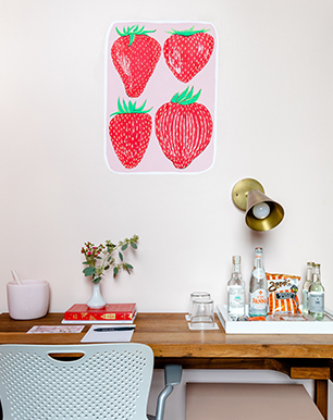 Desk with painted strawberries in the wall and beverages over the table 