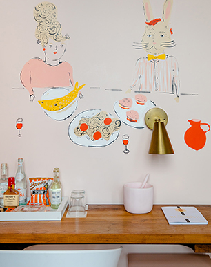 Work desk with beverages over the table and the wall painted with illustrations