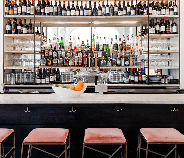 bar in a hotel with stools and beverages aligned in the wall