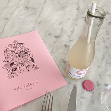 A beverage with a white straw next to a pink menu