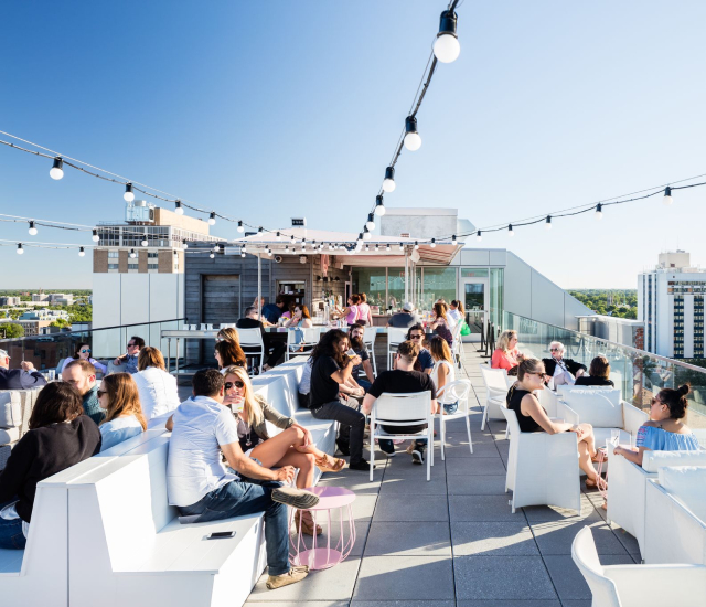 a rooftop bar with white chairs, and table