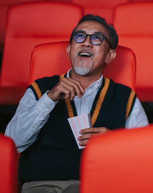man with glasses looking up while eating pop corn 