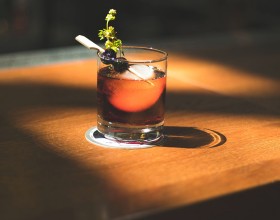 whiskey cocktail garnished with parsley and black cherries