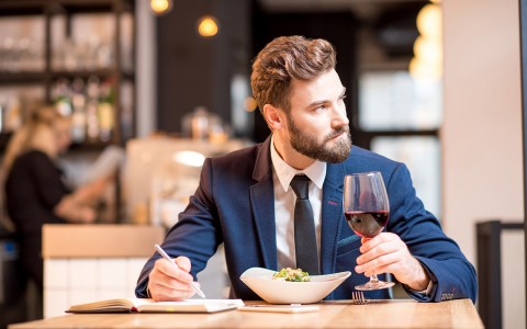 A business man sitting on a table enjoying a salad and a glass of wine