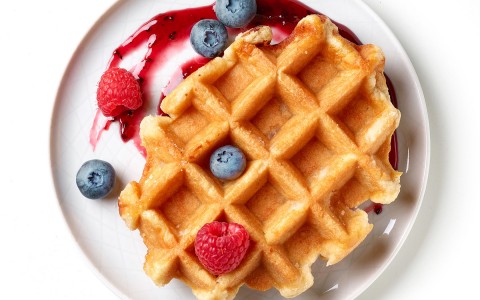 Top view of a waffle bathed in mix berries sauce