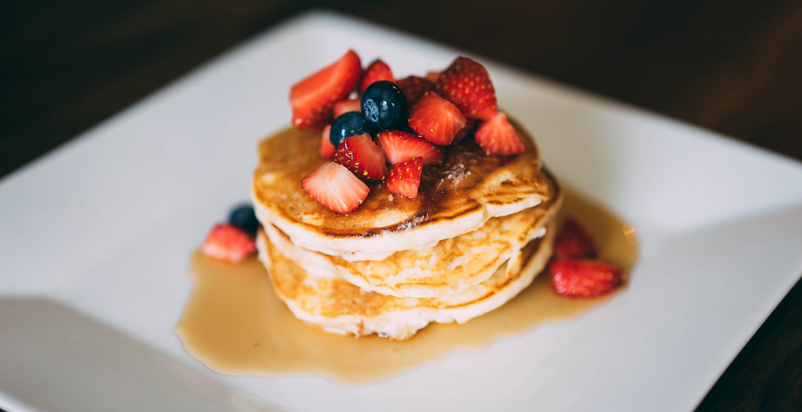 Some pancakes with maple syrup and berries on top 